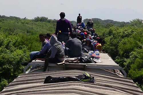 Unaccompanied minors ride atop the wagon of a freight train, known as La Bestia (The Beast) in Ixtepec